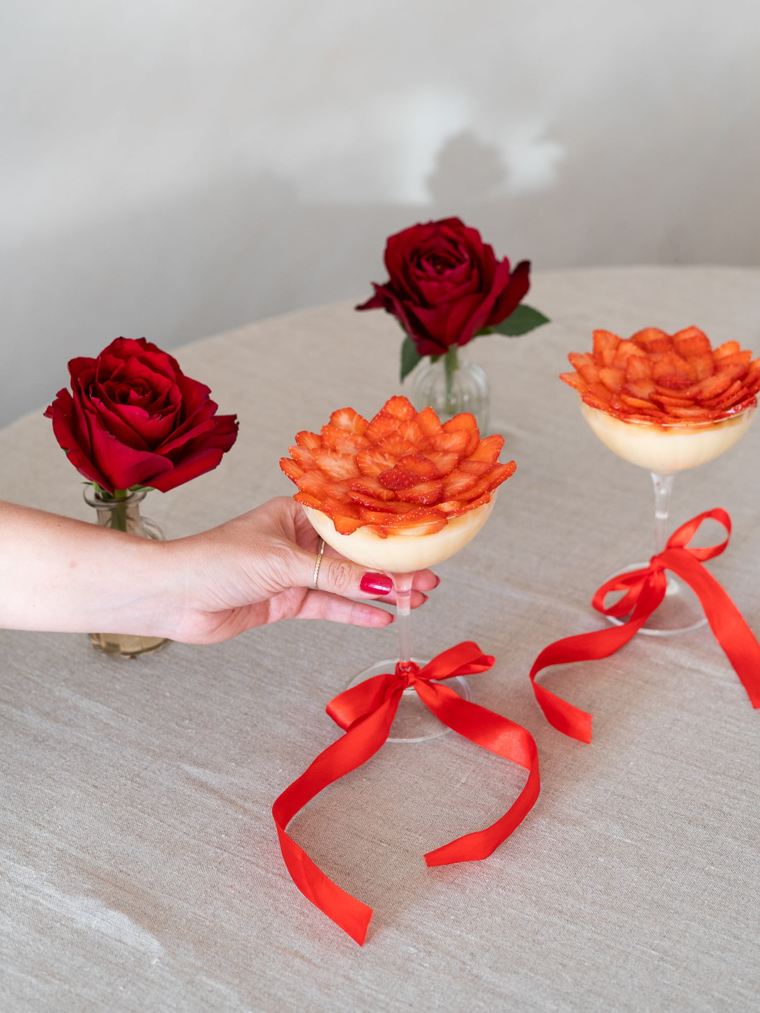 2. Il tocco finale sarà una fragola intera o un cuoricino posti al centro. Puoi decorare gli steli dei bicchieri con un fiocco rosso.