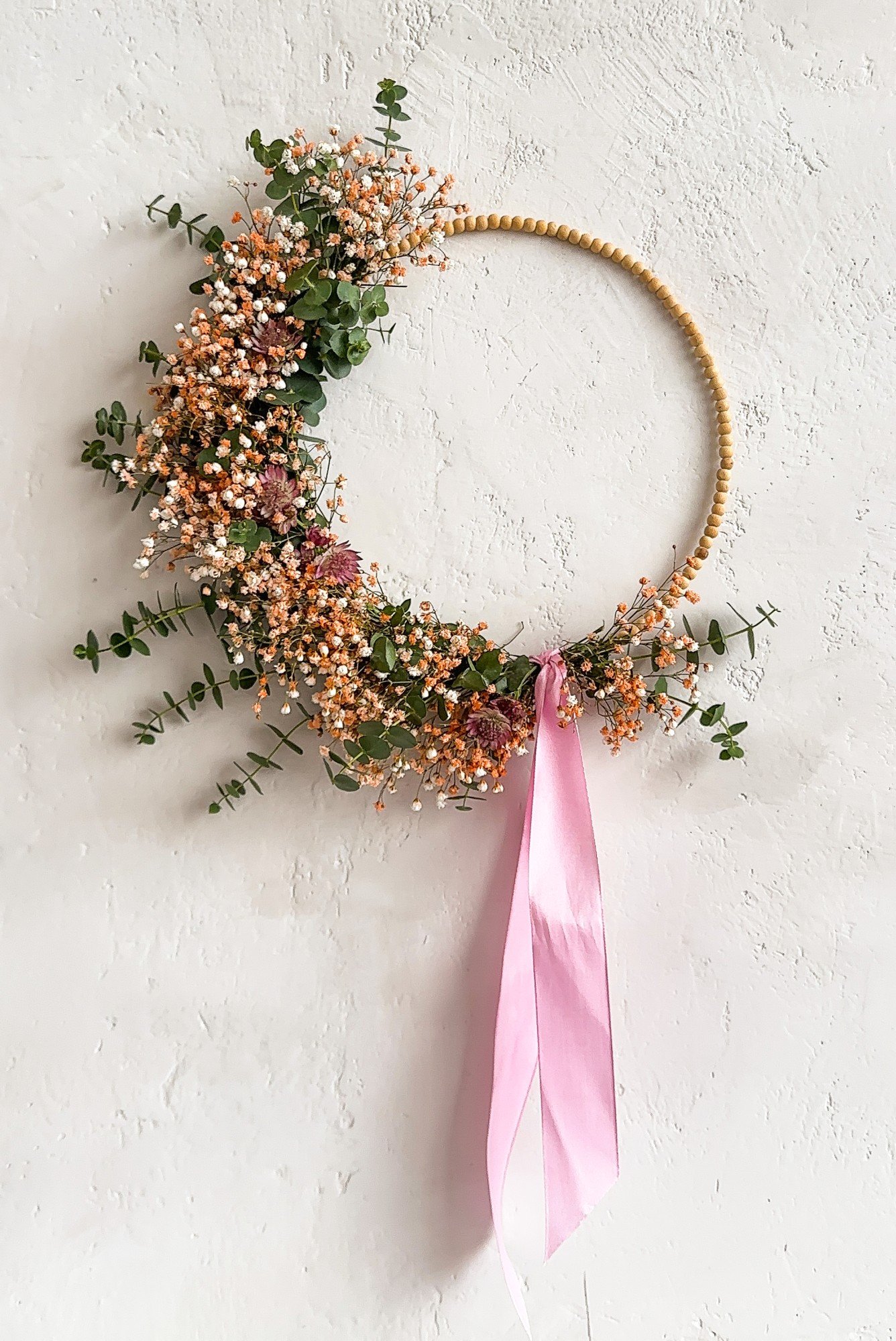 Ghirlanda primaverile con base di perline in legno.