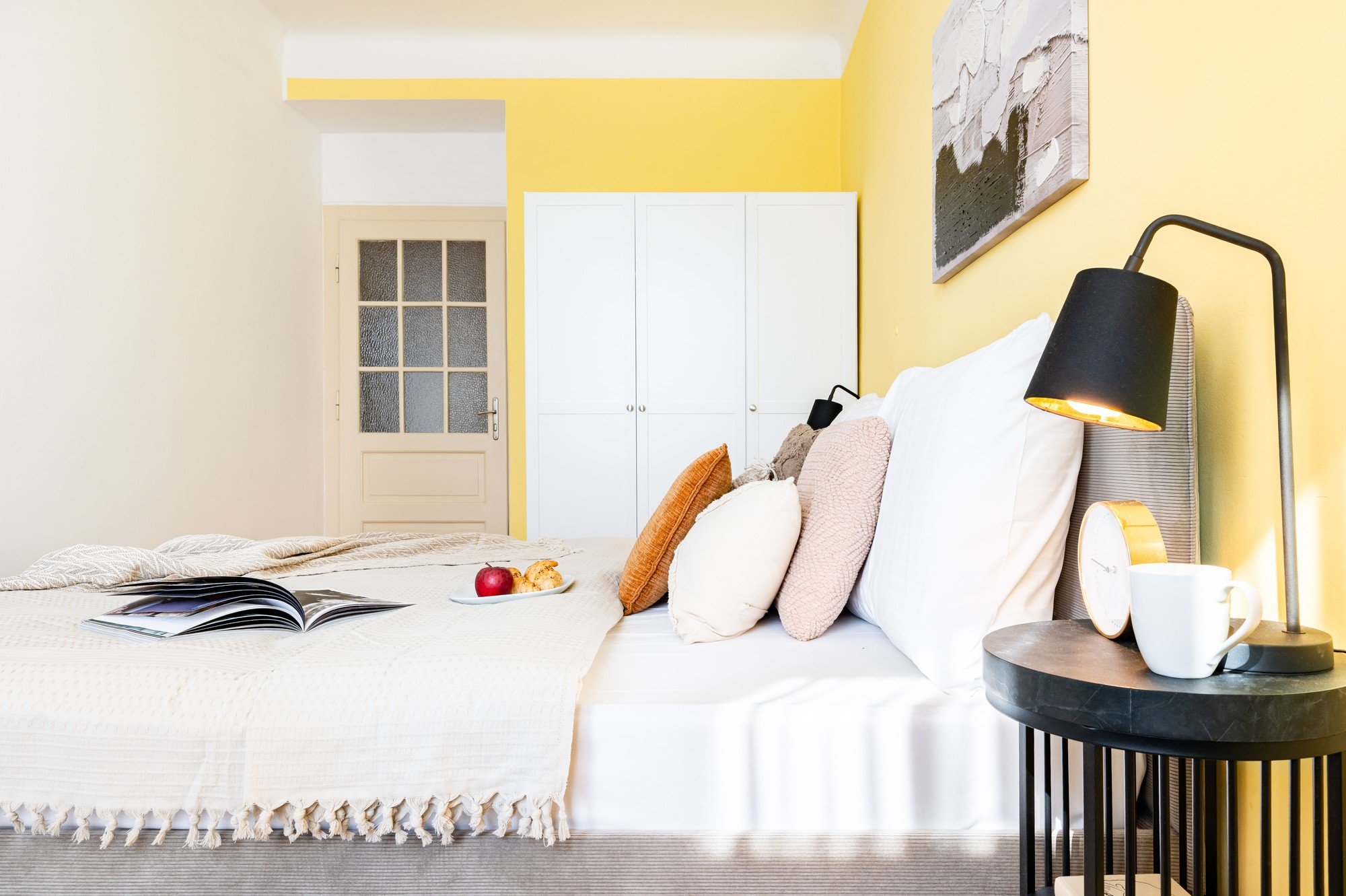 Ora lo spazio è fresco e armonioso, con accenti di giallo caldo, tessuti stratificati e dettagli che rendono la camera da letto un luogo accogliente e moderno in cui rilassarsi.